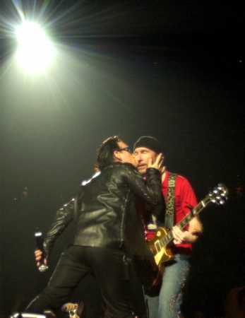 The Edge, right, receives a kiss from Bono during the U2 concert at the Continental Airlines Arena Friday, June 22, 2001. The show was the last performance of the North American leg of the 2001 Elevation tour. (AP Photo/Bill Kostroun)