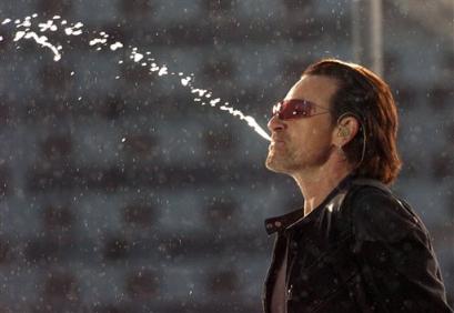 Bono spits water on stage as U2 perform their second song 'I Will Follow' at Croke Park stadium in Dublin, Friday June 24, 2005. ( AP Photo/PA, Haydn West)