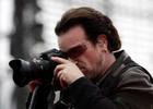 U2 vocalist Bono takes a snap with press photographers camera during the band's only concert in Switzerland at the Letzigrund stadium in Zurich July 18, 2005. REUTERS/Siggi Bucher