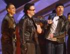 U2, from left, Adam Clayton, Bono, Larry Mullen, behind Bono, and The Edge joke around as they accept the award for best rock performance by a duo or group for 