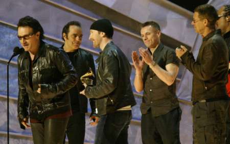U2 members Bono, The Edge, Larry Mullen and Adam Clayton (R) accept the Grammy Award for Record of the Year at the 44th Annual Grammy Awards in Los Angeles February 27, 2002. U2 won for their song "Walk On." Producer of the record Daniel Lanois is second from left. REUTERS/Gary Hershorn