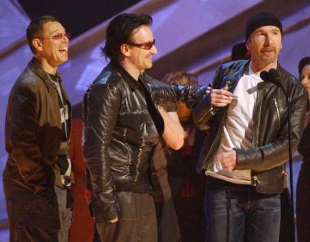 U2, from left, Adam Clayton, Bono, Larry Mullen, behind Bono, and The Edge joke around as they accept the award for best rock performance by a duo or group for "Elevation" during the 44th annual Grammy Awards, Wednesday, Feb. 27, 2002, in Los Angeles. (AP Photo/Kevork Djansezian)